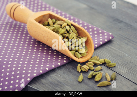 Graines de cardamome à sec en gros plan scoop sur fond de bois Banque D'Images