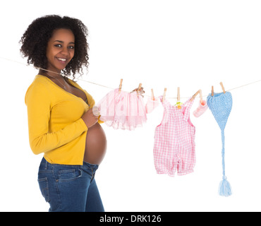 Happy pregnant african woman hanging blanchisserie bébé sur une ligne Banque D'Images