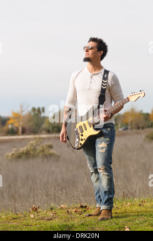 Un homme, musicien de rock jouant de sa guitare électrique à l'extérieur loin Banque D'Images