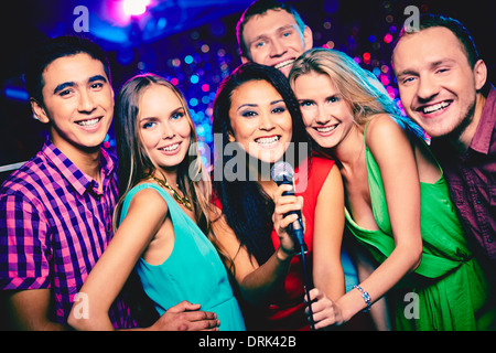 Portrait of happy les filles et les gars en chantant dans le microphone karaoke bar Banque D'Images