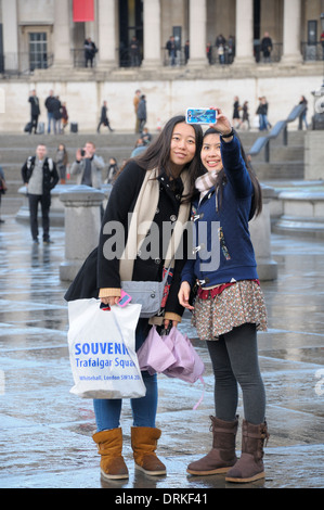 Londres, Angleterre, Royaume-Uni. Deux touristes japonais en prenant un en selfies Trafalgar Square, la National Gallery derrière Banque D'Images