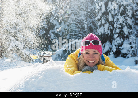 L'Autriche, l'état de Salzbourg, Altenmarkt-Zauchensee, Smiling young woman lying in snow, portrait Banque D'Images