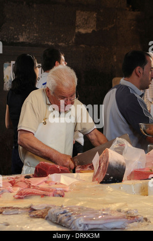 Les vendeurs de poisson couper le poisson dans la pescheria, marché aux poissons Catane, Sicile Banque D'Images