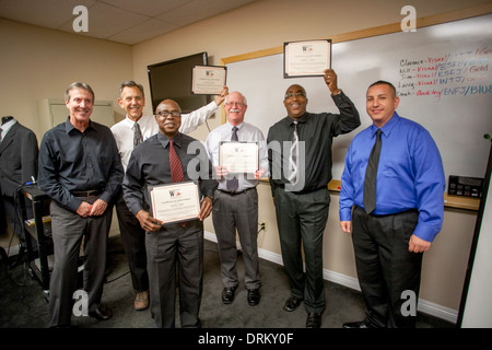 Les participants à un atelier de la carrière d''Men' affichent fièrement leurs certifications nationales en service des diplômes sur l'obtention de leur diplôme, le port d'une tenue d'affaires nouvelles de travail de placards, une organisation d'aider les chômeurs et le marié robe pour le succès Banque D'Images