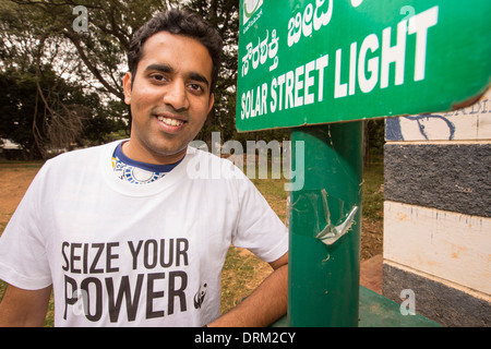 Un jeune homme portant un pouvoir saisir votre Tshirt, une campagne menée par le WWF pour promouvoir l'énergie renouvelable, à côté d'une lumière solaire dans un parc Banque D'Images