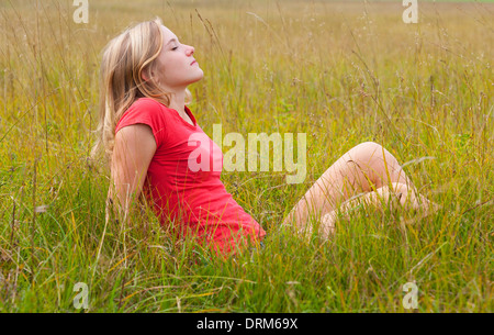 L'Autriche, Salzkammergut, Mondsee, young woman sitting in a meadow Banque D'Images