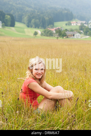 L'Autriche, Salzkammergut, Mondsee, young woman sitting in a meadow Banque D'Images