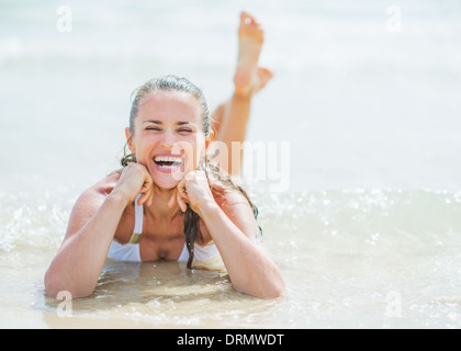 Happy young woman laying on sea shore Banque D'Images