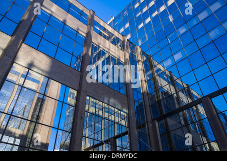 Deux blocs de verre moderne bureau debout à angle droit l'un à l'autre reflètent l'un l'autre et d'un certain nombre d'autres blocs. Banque D'Images