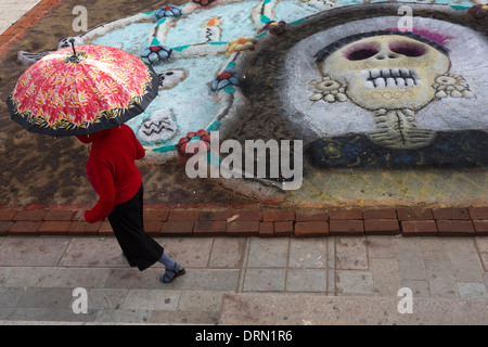 Une femme marche à côté de l'une des représentations de Catrina tirés sur le terrain le jour de la mort. Banque D'Images