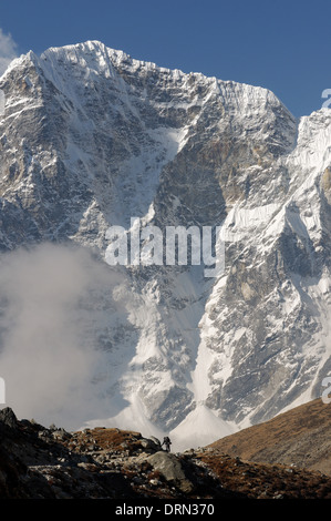 La petite figure d'un trekker est éclipsé par la face est de Taboche sur le camp de base de l'everest trek Banque D'Images