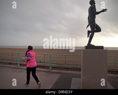 Un jogger sur le front de mer de Brighton passe devant la statue de Steve Ovett Banque D'Images