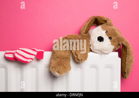 La chambre rose avec un ours en peluche et une paire de mitaines placé sur le dessus d'un radiateur de chauffage. Banque D'Images