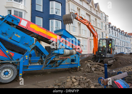 Après une semaine de fortes marées, les ondes de tempête et des vents violents, de la promenade du front de mer d'Aberystwyth au Pays de Galles a été dévastée, avec des millions d'€ de dommages. Le fracas des vagues de poing à un grand trou dans le mur de la mer s'est effondré et l'emblématique d'Aberystwyth, promenade victorienne d'abris, qui a résisté pendant plus de 100 ans. Cette photo a été prise le mercredi 8 janvier 2014, le jour où le conseil a commencé à essayer et effacer les milliers de tonnes de gravats plage front de mer au large de la route. Banque D'Images