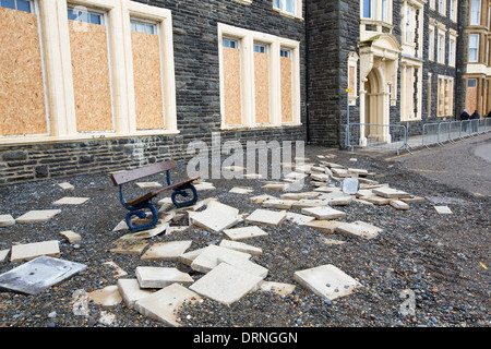 Après une semaine de fortes marées, les ondes de tempête et des vents violents, de la promenade du front de mer d'Aberystwyth au Pays de Galles a été dévastée, avec des millions d'€ de dommages. Le fracas des vagues de poing à un grand trou dans le mur de la mer s'est effondré et l'emblématique d'Aberystwyth, promenade victorienne d'abris, qui a résisté pendant plus de 100 ans. Cette photo a été prise le mercredi 8 janvier 2014, le jour où le conseil a commencé à essayer et effacer les milliers de tonnes de gravats plage front de mer au large de la route. Ici dalles ont été déchirés et jetés 30 pieds de l'autre côté de la rue. Banque D'Images