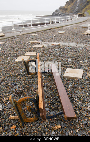 Après une semaine de fortes marées, les ondes de tempête et des vents violents, de la promenade du front de mer d'Aberystwyth au Pays de Galles a été dévastée, avec des millions d'€ de dommages. Le fracas des vagues de poing à un grand trou dans le mur de la mer s'est effondré et l'emblématique d'Aberystwyth, promenade victorienne d'abris, qui a résisté pendant plus de 100 ans. Cette photo a été prise le mercredi 8 janvier 2014, le jour où le conseil a commencé à essayer et effacer les milliers de tonnes de gravats plage front de mer au large de la route. Ici dalles ont été déchirés et jetés 30 pieds de l'autre côté de la rue. Banque D'Images