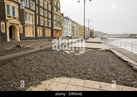 Après une semaine de fortes marées, les ondes de tempête et des vents violents, de la promenade du front de mer d'Aberystwyth au Pays de Galles a été dévastée, avec des millions d'€ de dommages. Le fracas des vagues de poing à un grand trou dans le mur de la mer s'est effondré et l'emblématique d'Aberystwyth, promenade victorienne d'abris, qui a résisté pendant plus de 100 ans. Cette photo a été prise le mercredi 8 janvier 2014, le jour où le conseil a commencé à essayer et effacer les milliers de tonnes de gravats plage front de mer au large de la route. Ici dalles ont été déchirés et jetés 30 pieds de l'autre côté de la rue. Banque D'Images