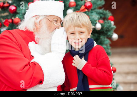 Santa Claus chuchotant à l'oreille du garçon Banque D'Images