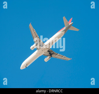 Grand avion de passagers en vol avec le train roulant vers le bas à mesure qu'il arrive à la terre isolé sur un fond de ciel bleu Banque D'Images