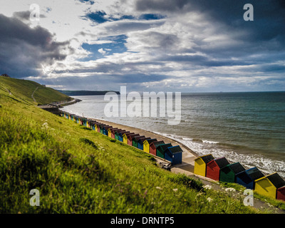 Cabanes de plage au pied de West Cliff, Whitby, North Yorkshire. Banque D'Images