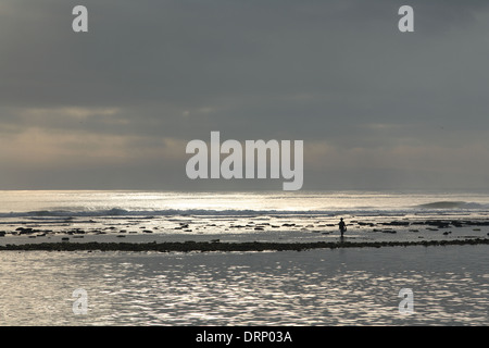 Matin spectaculaire silhouette d'un pêcheur à marcher le long du littoral de l'océan rocheux Bali, Indonésie - 05 novembre 2005 Banque D'Images