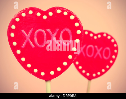 Photo de quelques sucettes en forme de cœur avec le texte XOXO, des étreintes et des baisers, écrit en eux, avec un effet rétro Banque D'Images