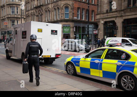 Manchester, 874-6448, au Royaume-Uni. 30 janvier, 2014. "Police suivez ce van' Greater Manchester Police offrant une sécurité supplémentaire pour les transferts en espèces 874-6448 que Loomis employé transfère de cas de sécurité stationnées van. "Une commande permanente pour les véhicules de la police sur les fonctions générales d'escorter les transporteurs de véhicules qu'ils viennent sur les vols a été particulièrement fructueuse en rendant difficile pour les criminels de planifier leurs activités autour de camionnettes de livraison sans escorte. loomis fournit des solutions pour le transport de fonds, de la collecte et de la livraison en espèces. Banque D'Images