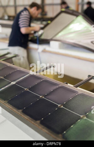 Dübendorf, Suisse. , 29 janv. 2014 : Une cellule solaire couverts du gouvernail de l'avion 'Solar Impulse 2' (HB-SIB) qui est actuellement construit à Dübendorf (Zurich), Suisse. Dans l'arrière-plan, un ingénieur de l'équipe de projet travaille sur une partie de carénage. Pionnier de l'aviation suisse Bertrand Piccard a l'intention de voler l'avion solaire futuriste dans le monde en 2015. Crédit : Erik Tham/Alamy Live News Banque D'Images