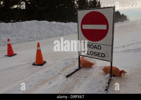 Un signe de fermeture de route une route blocs après véhicules sont piégés dans la neige d'hiver accompagnée de vent et de fortes conditions de blizzard Banque D'Images