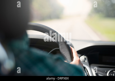 Personne en voyage, la conduite d'une voiture. Maintenant la roue et à la recherche lors d'une route vide. Banque D'Images