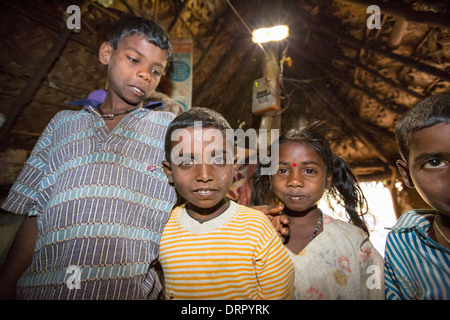 Une famille intouchable dans leur hutte, éclairé par une lumière électrique, alimenté par un panneau solaire de format A4, Banque D'Images