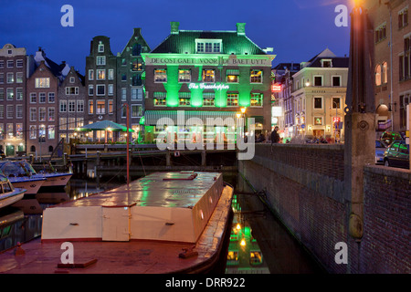 Amsterdam par nuit, barge sur un canal et bâtiments historiques dans le centre ancien de la ville, au nord de la Hollande, les Pays-Bas. Banque D'Images