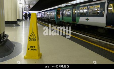 Avis de santé et de sécurité un nouveau plancher à une plate-forme humide London railway station Banque D'Images
