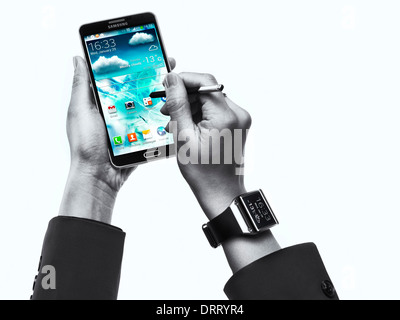 Femme portant Samsung Galaxy Gear watch et à l'aide du smartphone Galaxy Note III isolé sur fond blanc Banque D'Images