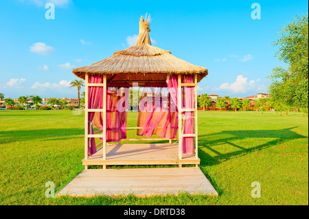 Gazebo au toit de chaume sur une pelouse verte Banque D'Images