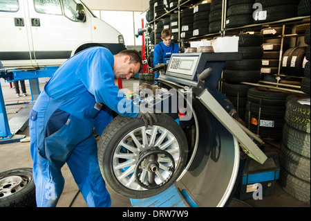 Un mécanicien de voiture équilibre une roue de voiture après avoir installé un nouveau pneu sur une jante. Banque D'Images