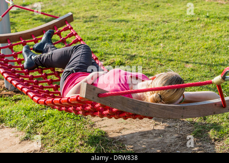 Jeune femme repose sur un hamac dans un jardin Banque D'Images