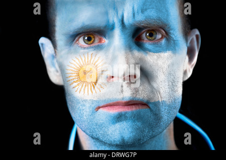 Un regard intense d'un supporter de football avec leur visage peint avec le drapeau argentin. Banque D'Images