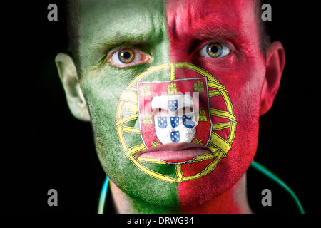 Un regard intense d'un supporter de football avec leur visage peint avec le drapeau portugais. Banque D'Images