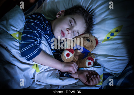 Enfant endormi avec son ours en peluche. Banque D'Images