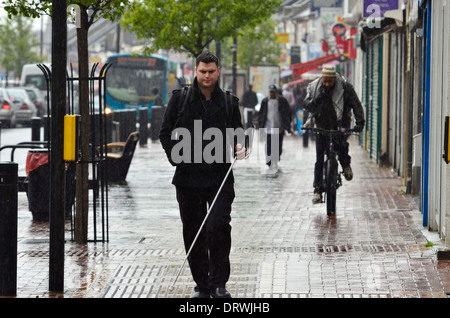 Stick Blanc aveugle qui n'a marcher sur une chaussée mouillée pendant la pluie douche à Luton Banque D'Images