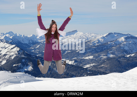 Jeune femme sautant de joie et de bonheur en hiver dans les montagnes couvertes de neige Banque D'Images