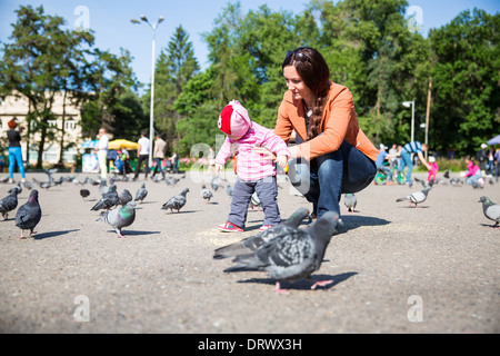 Enfant fille et maman jouant avec des colombes en ville. L'utiliser pour bébé, éducation ou le concept d'amour Banque D'Images