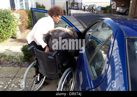 United Kingdom West Sussex une femme âgée s'aider entre soignant d'obtenir dans une voiture Banque D'Images