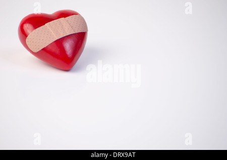 Coeur rouge en plastique avec bandage dans le coin de l'image, place à l'exemplaire. Banque D'Images