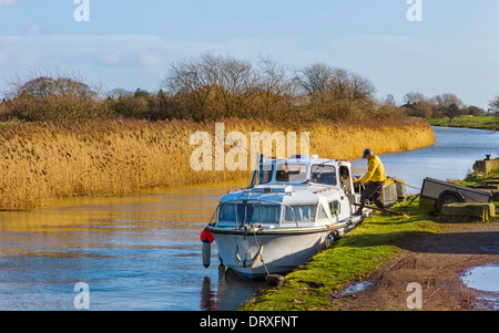 Un homme de déchargements des marchandises d'un petit bateau sur la rivière sur une coque de la matinée d'hiver près de Beverley, Yorkshire, UK. Banque D'Images