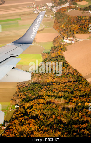 La préparation de l'avion pour l'atterrissage, tourné à partir de la fenêtre, montrant le logo flyniki sur l'aile d'avion, de vert et de marron et les champs de la forêt Banque D'Images