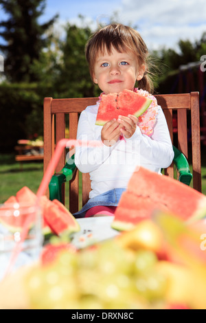 Petite fille mangeant une pastèque dans le jardin Banque D'Images