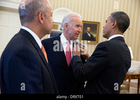 Le président américain Barack Obama ajuste le Vice-président Joe Biden's Pin drapeau américain pendant qu'ils attendent dans le bureau ovale avec Jeh Johnson, avant d'annoncer que Johnson le candidat proposé au poste de secrétaire du département de la sécurité intérieure, 18 octobre 2013 à Washington, DC. Banque D'Images