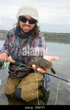 Montre un pêcheur de poissons chabot qu'il a capturé dans l'Arctique. Banque D'Images